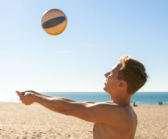Man bumping a volleyball on the beach